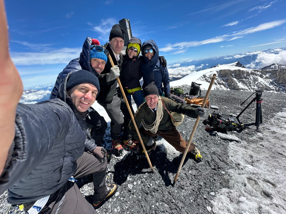 Gruppe von Menschen auf einem verschneiten Berggipfel.