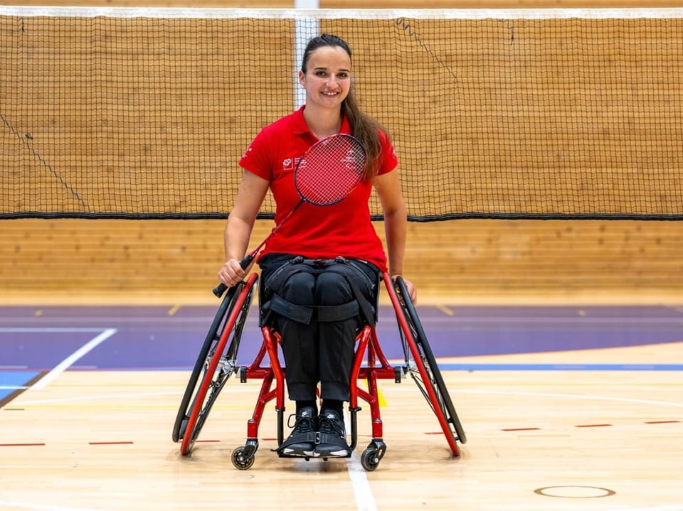 Frau im Rollstuhl mit Badmintonschläger auf dem Spielfeld.