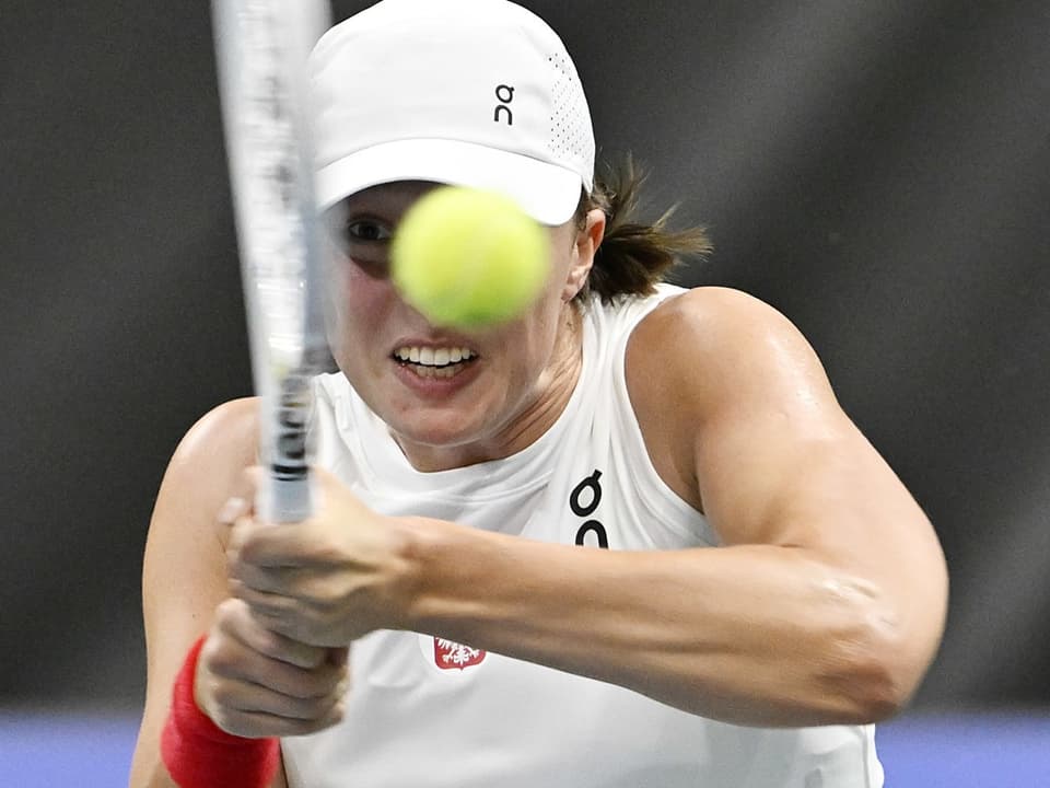 Tennisspielerin mit weissem Cap und Schläger konzentriert auf Ball.