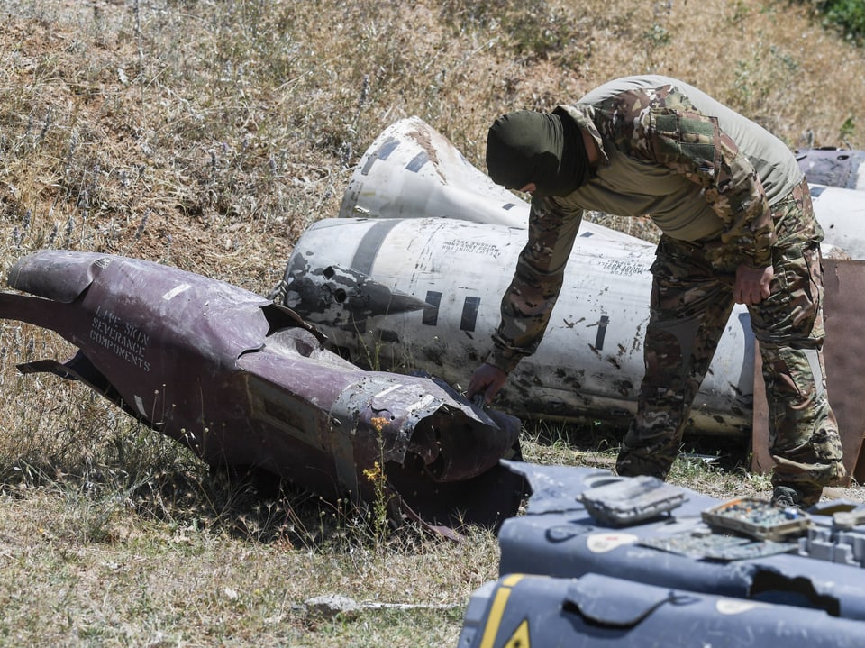 Soldat untersucht beschädigte Raketenteile auf Feld.