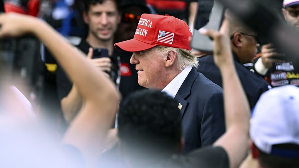 Donald Trump in roter Mütze in einer Menschenmenge.