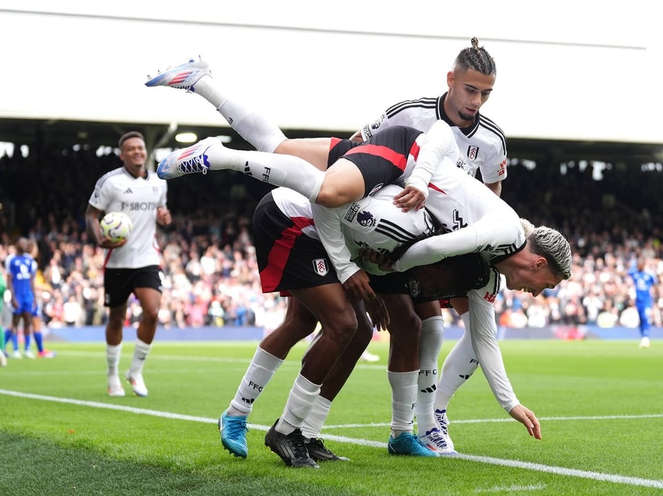 Iwobi gebeugt, Pereira auf seinem Rücken mit den Beinen nach oben