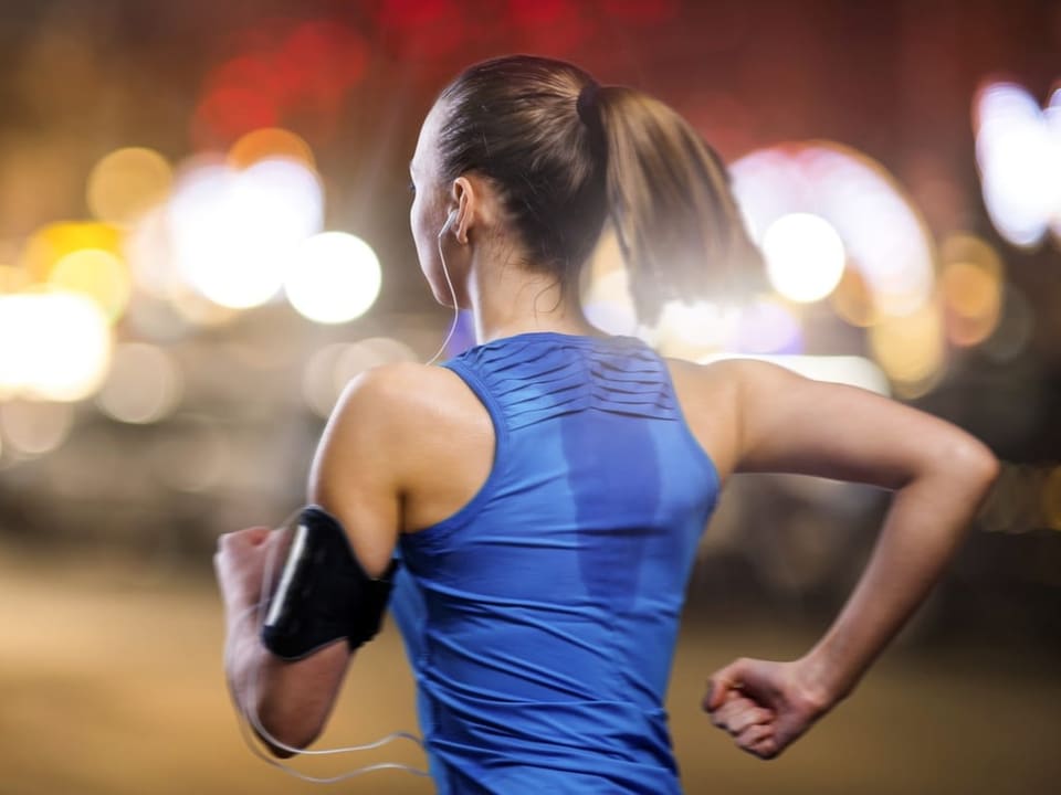 Woman jogging on blurred street at night.