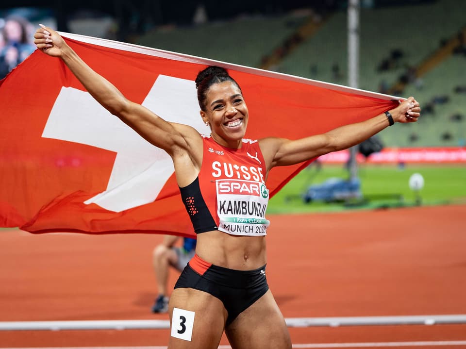 Sportlerin hält Schweizer Flagge im Stadion hoch.