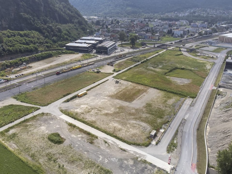 Luftbild einer Industriebrache neben einem Bahngleis in einer Stadt.