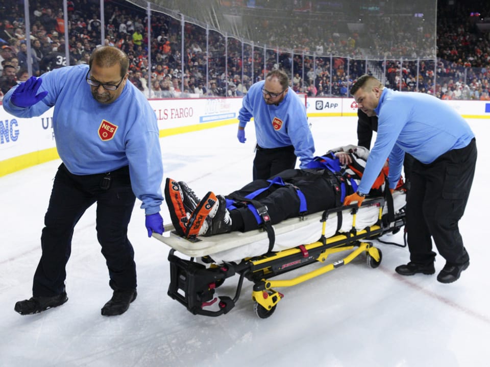 Eishockeyspieler auf Trage, von Sanitätern betreut.