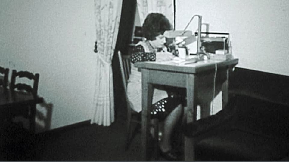 Schwarz-weiss-Aufnahme einer Arbeiterin an einem Tischchen.