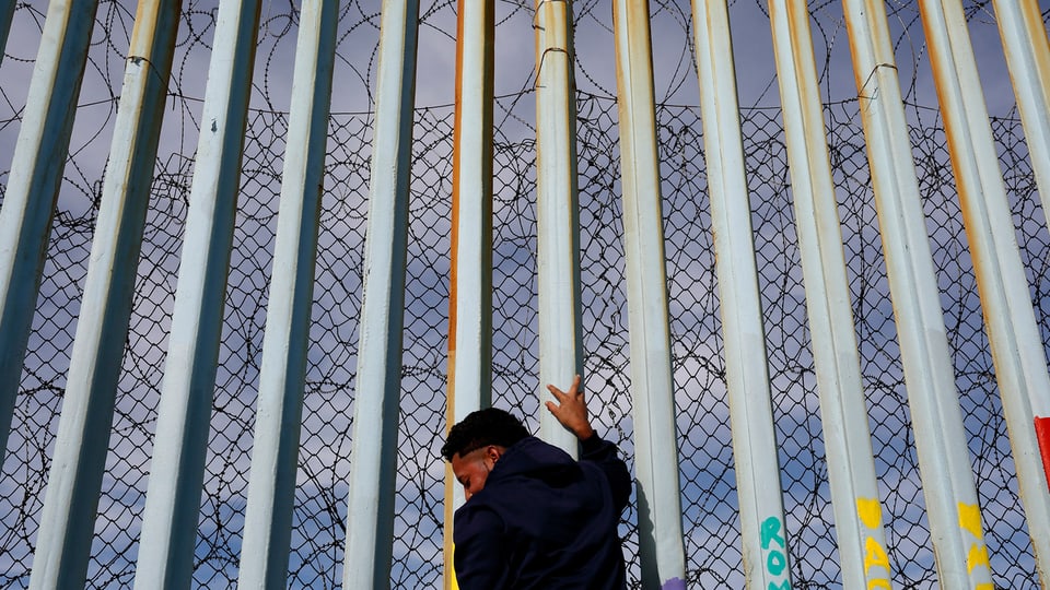 Mann steht an der Mauer am Strand von Tijuana, Mexiko