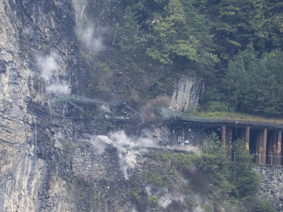 Sprengung an einer Felswand neben einem Bahntunnel.