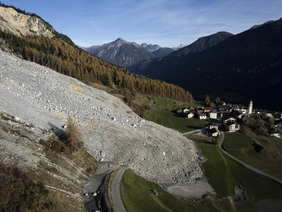 Luftaufnahme eines Erdrutsches neben einem Dorf in den Bergen.