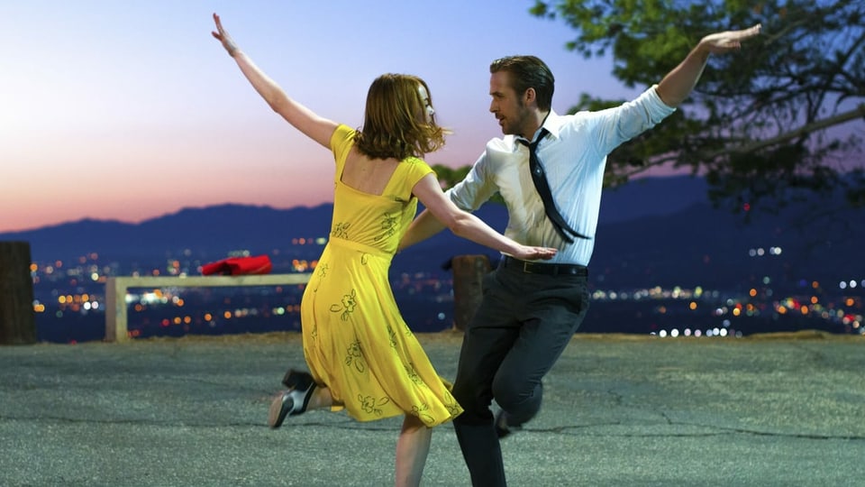 Eine Frau im gelben Kleid tanzt mit einem Mann im Anzug.