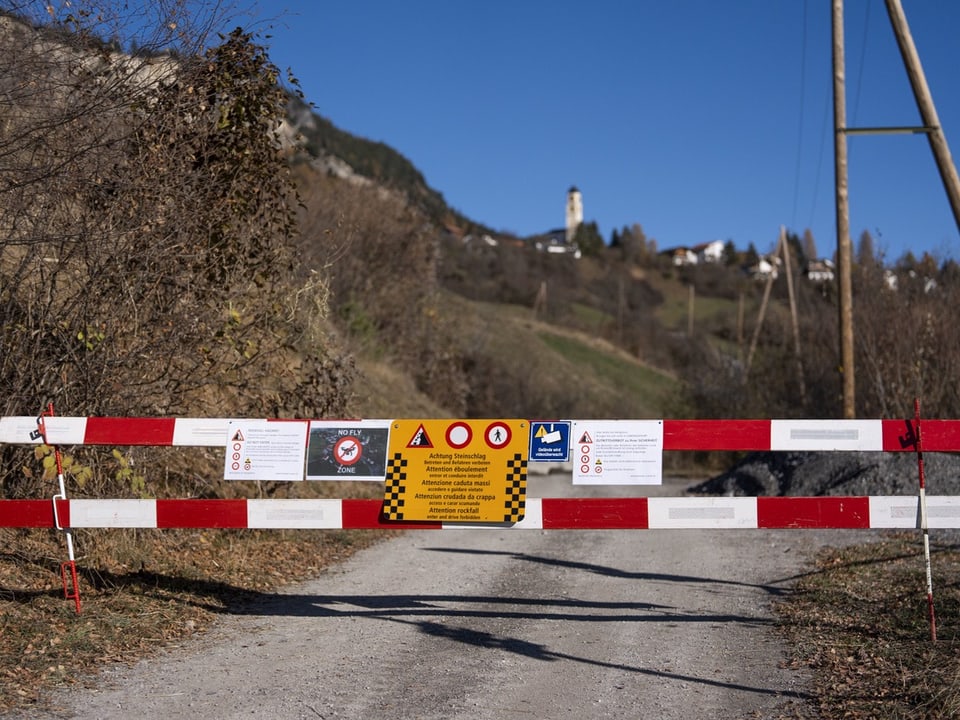 Absperrungen auf einer Strasse, im Hintergrund ein Dorf