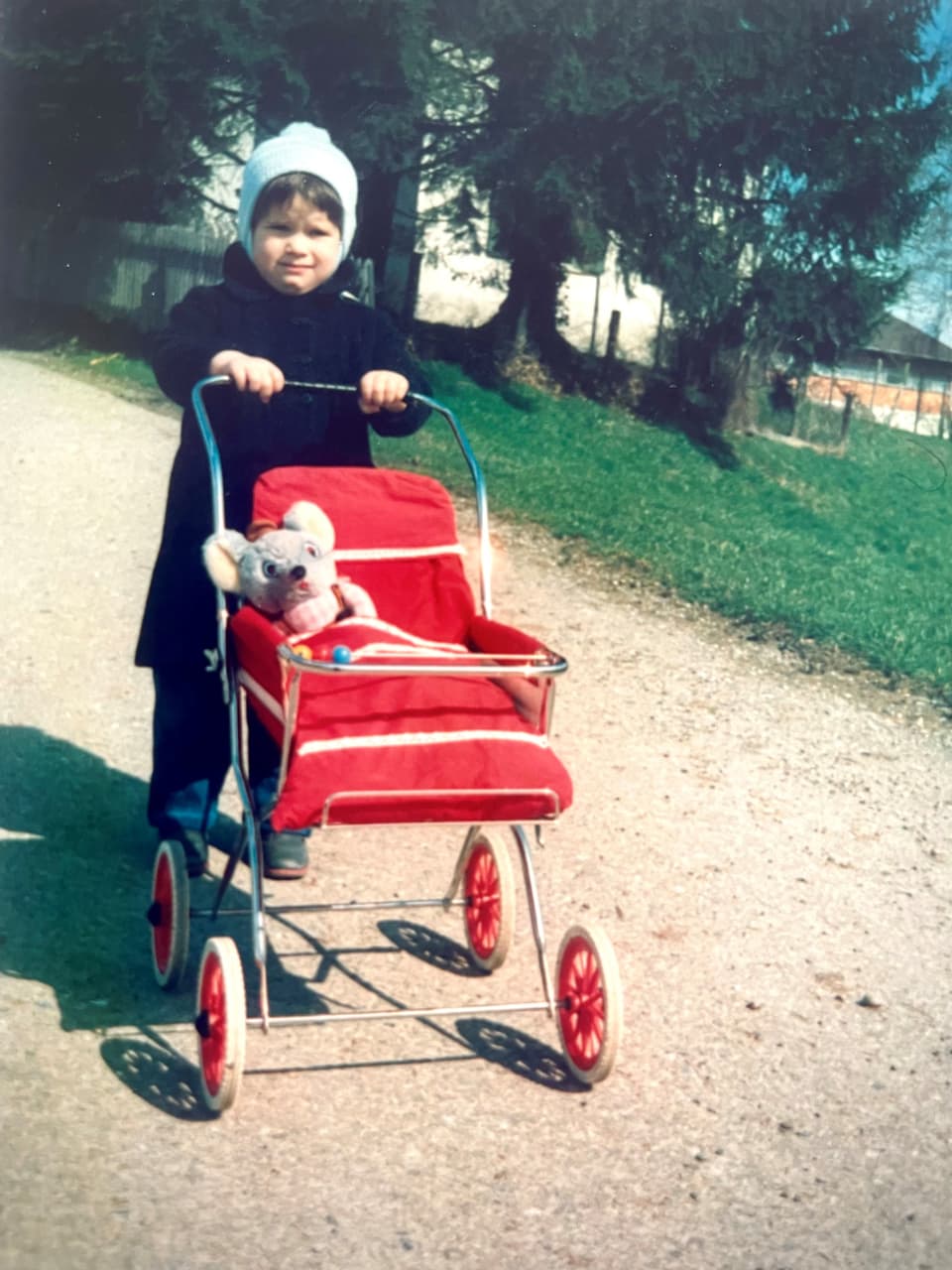 Sabrina Lehmann als Kind mit einem Kinderwagen mit einer Plüschtieraus drin.