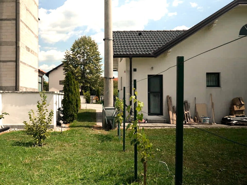 Haus mit Garten und Zaun bei sonnigem Wetter.