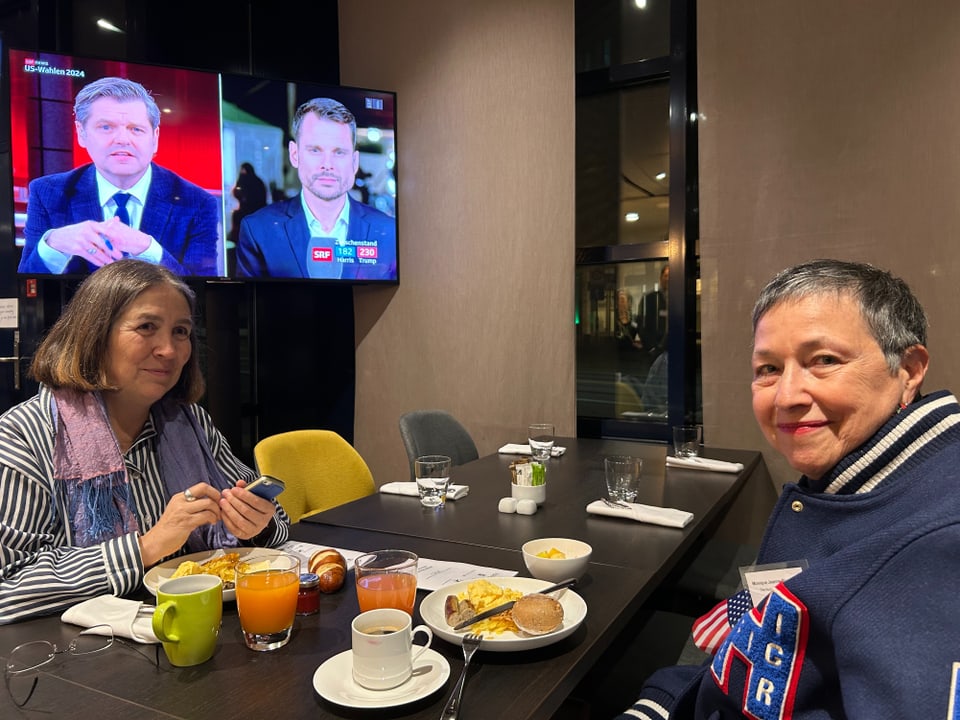 Zwei Personen frühstücken vor einem Fernseher.