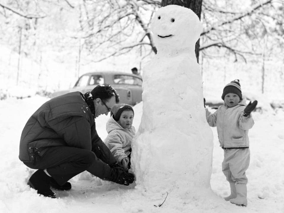 Eine Familie baut einen Schneemann