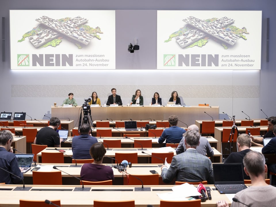 Presskonferenz mit Podium und Publikum in einem Konferenzraum.