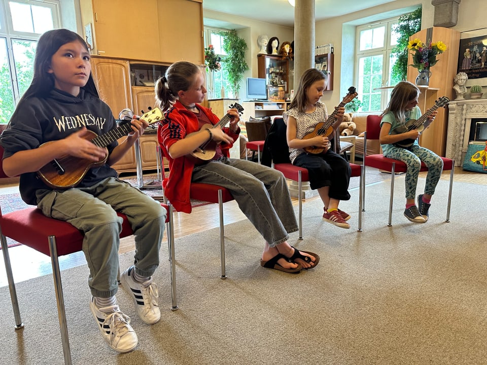 Vier Kinder spielen auf ihrer Ukulele