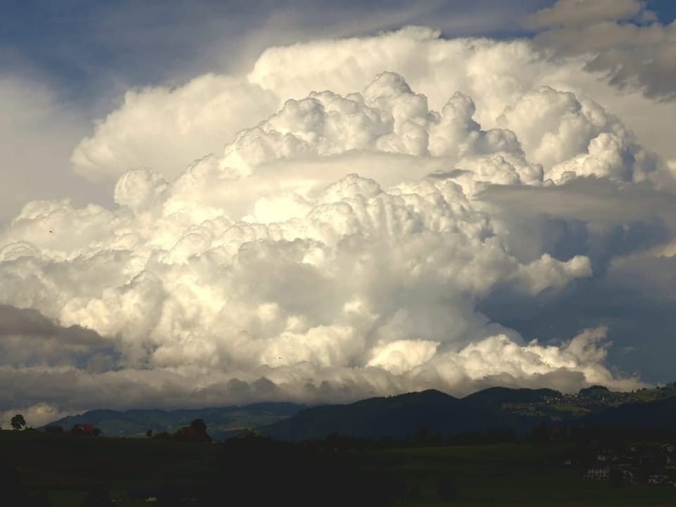 Gewaltige Wolkenformation über einer Hügellandschaft.