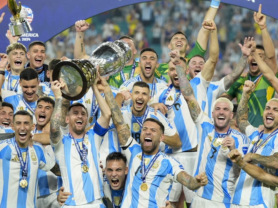 Argentinische Fussballmannschaft feiert mit Pokal.