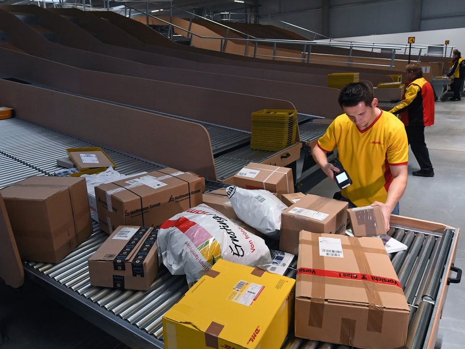 Paketzusteller in gelben Hemden sortieren Pakete.