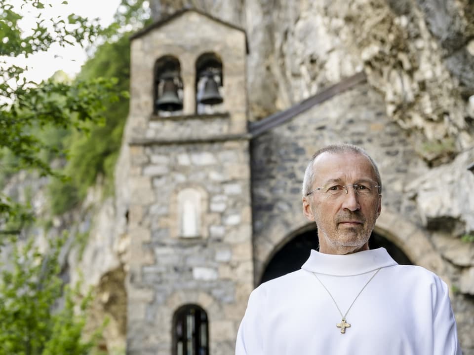 Ein Geistlicher in weissem Gewand mit einer Kreuz-Kette um den Hals.