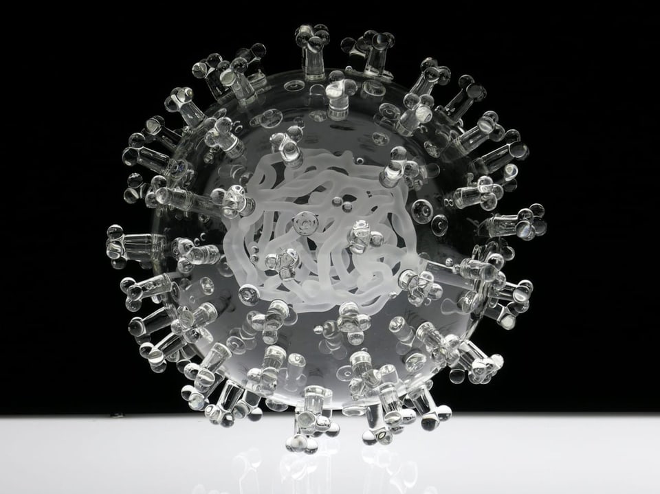 Glasmodell eines Virus auf schwarzem Hintergrund.