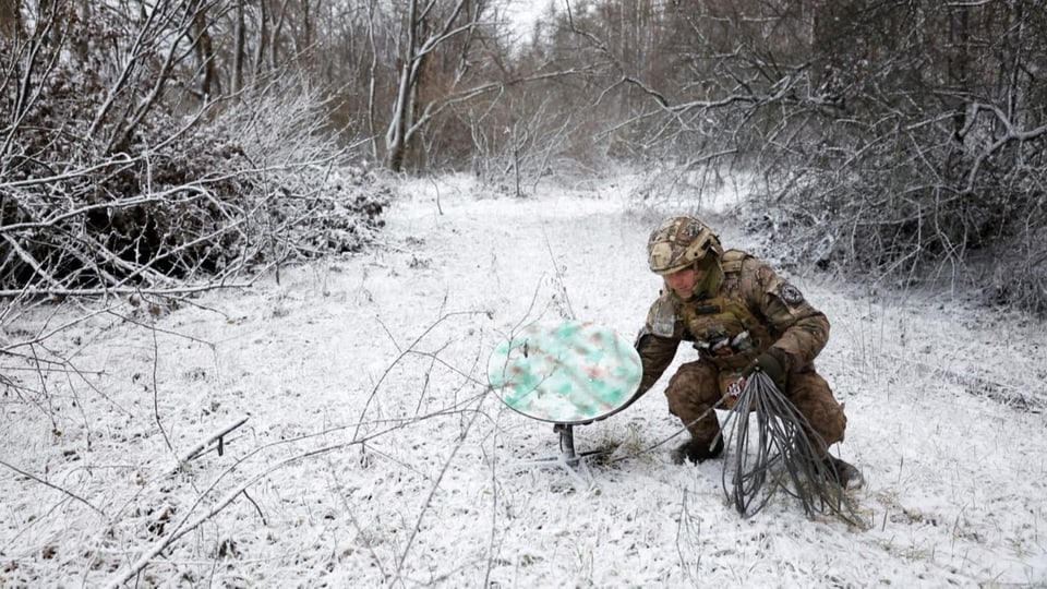 Ein ukrainischer Soldat räumt einen Starlink ab.