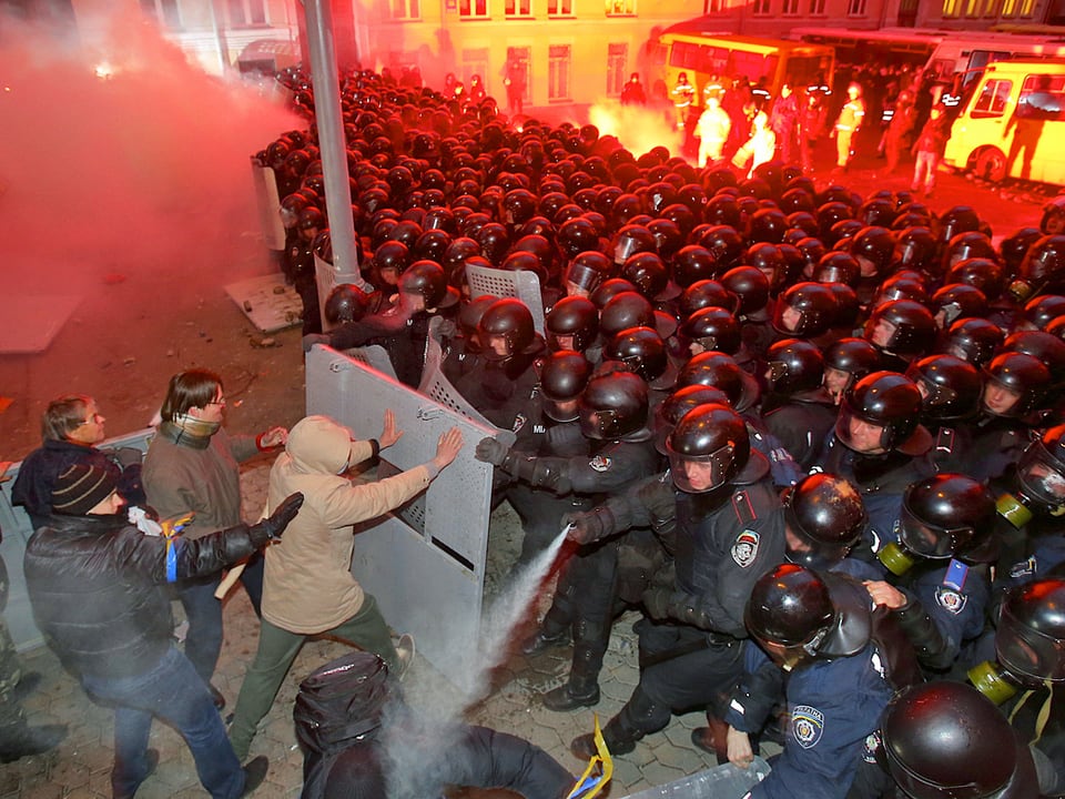 Demonstranten greifen Polizisten an.