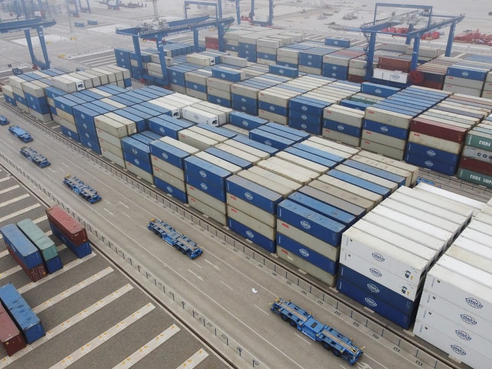 Luftaufnahme von gestapelten Frachtcontainern im Hafen.