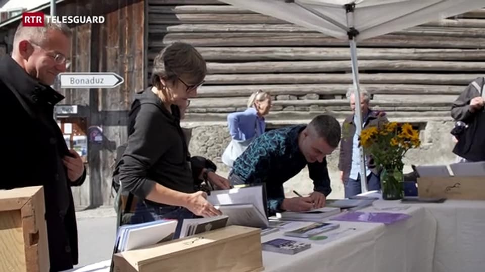 Menschen unterschreiben an einem Tisch unter einem Pavillon.