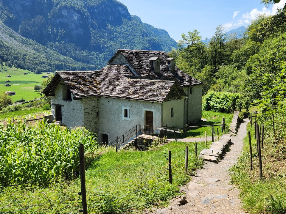 Steinhaus in den Bergen mit Gartenweg im Sommer.