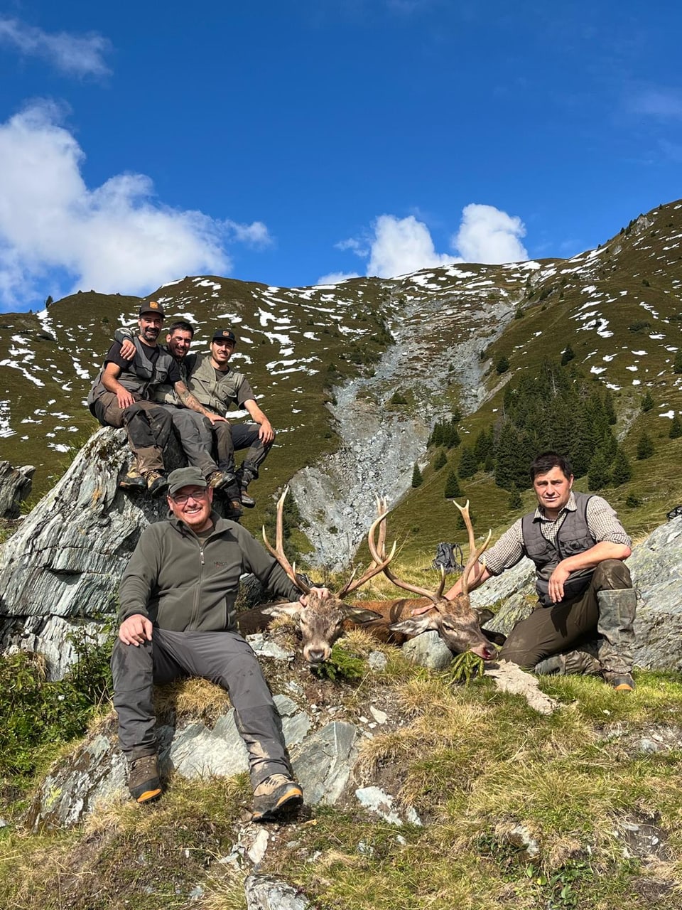 Gruppe von Jägern mit erlegtem Hirsch in den Bergen.