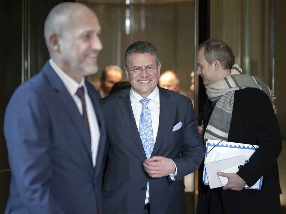 Männer in Anzügen unterhalten sich in einem Bürogebäude.