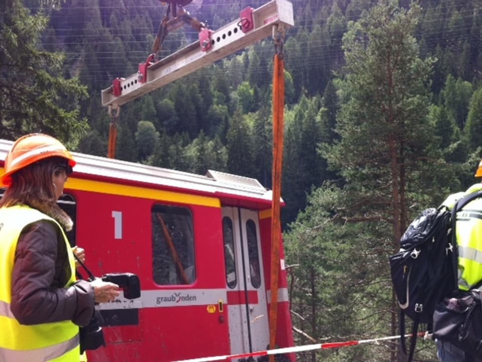 Mit einem Schienenkran wird der entgleiste Wagen zurück auf die Gleise gestellt.