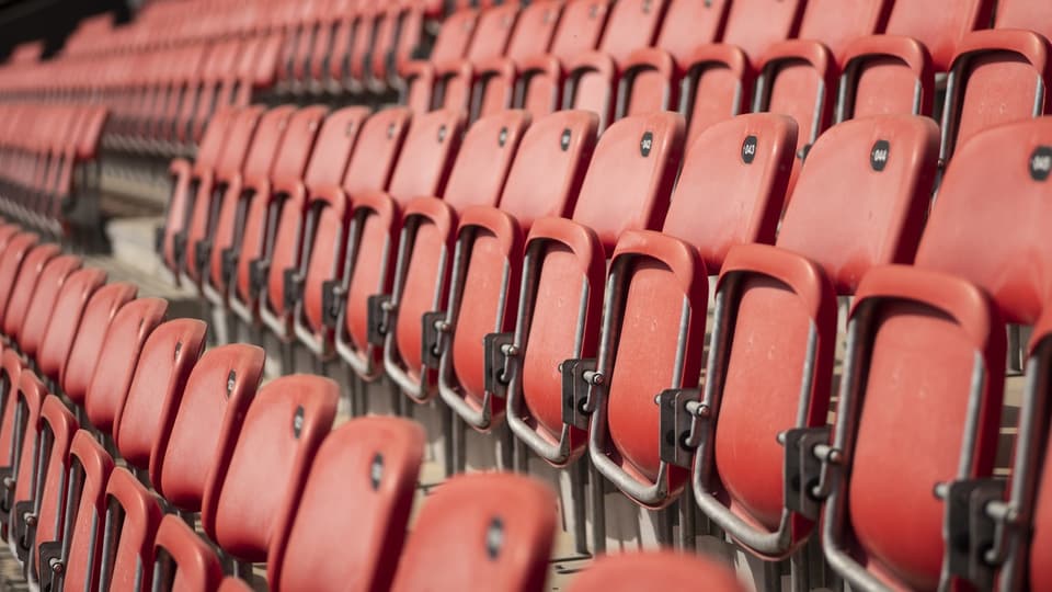 Reihen leerer roter Sitze in einem Stadion.