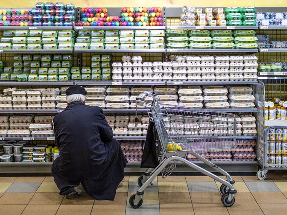 Person wählt Eier im Supermarkt aus.