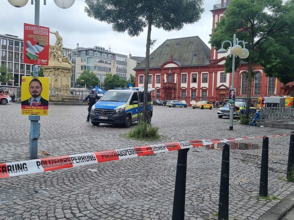 Absperrband und Polizeiauto auf einem Platz mit historischen Gebäuden