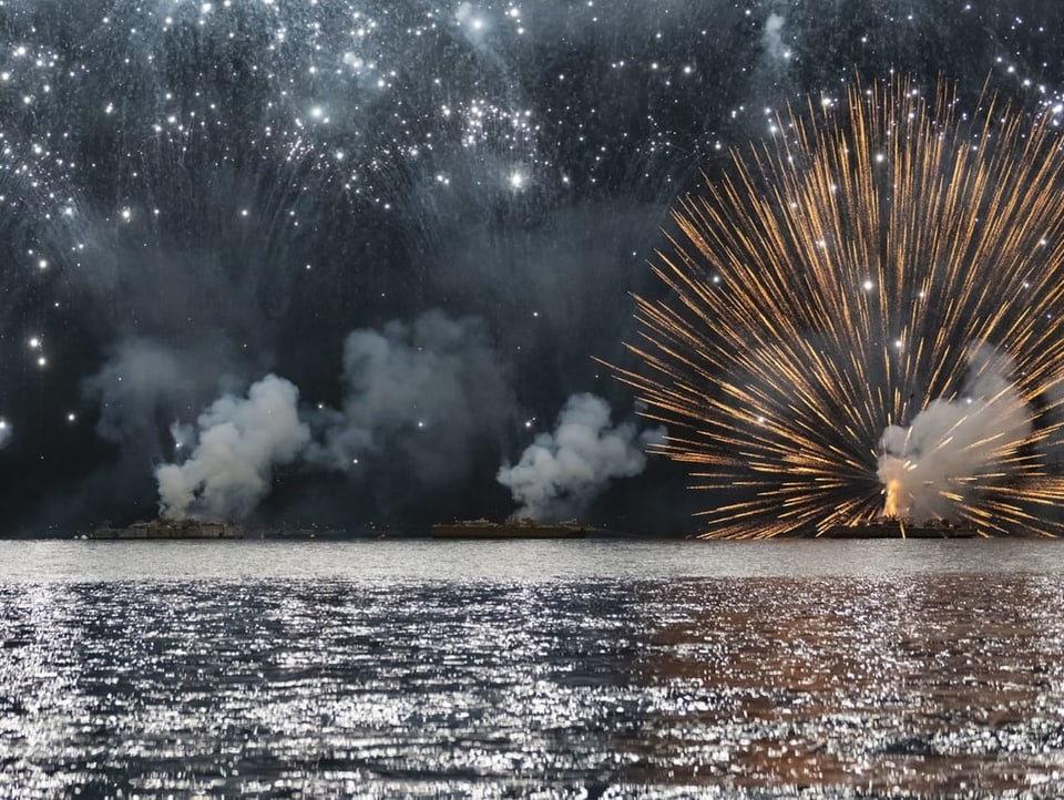 Feuerwerk und Rauch über einem See.