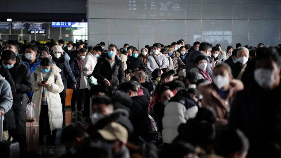 Chinesinnen und Chinesen warten auf ihre Züge an einem Bahnhof.