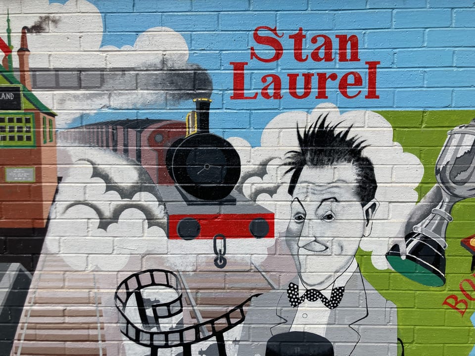 Wandgemälde von Stan Laurel mit Dampflok und Filmrolle.
