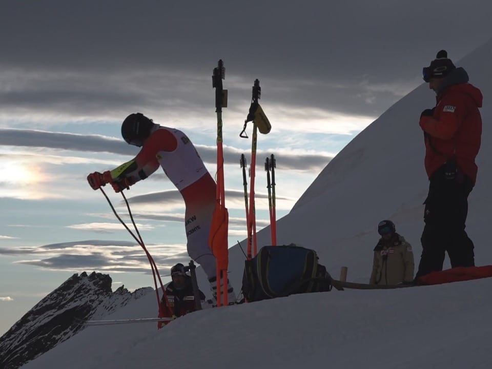 Skifahrer bereitet sich auf Abfahrt auf schneebedecktem Berg vor.