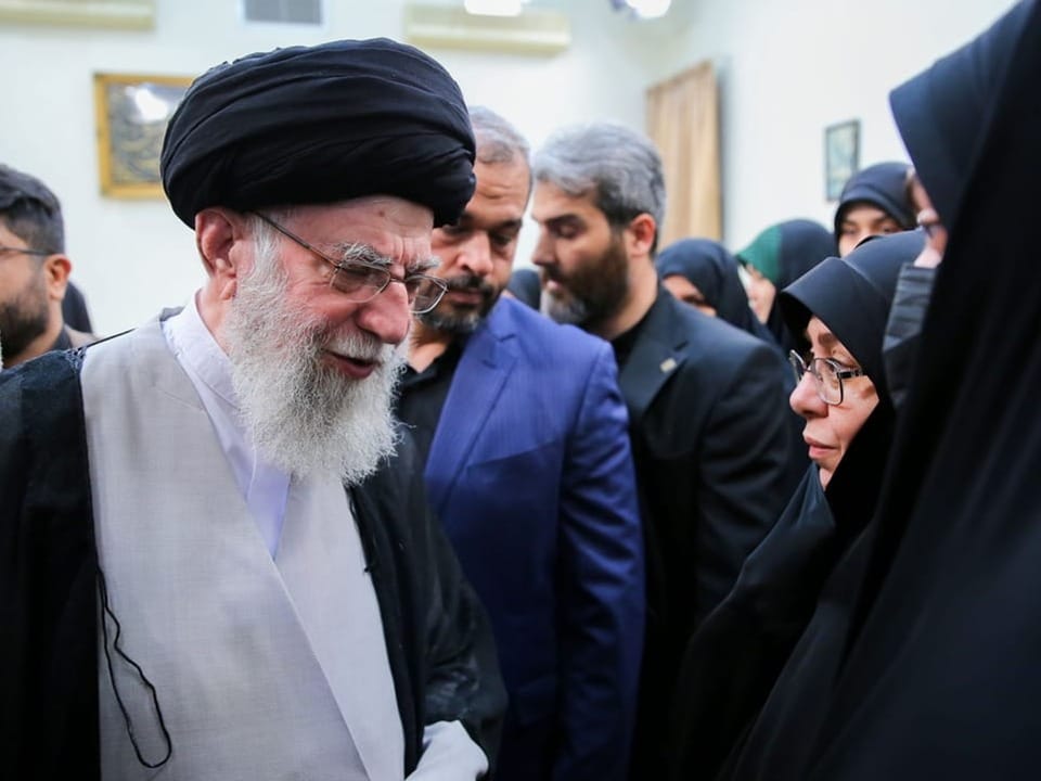 Chamenei geht mit gesenktem Kopf an vermummten Frauen vorbei