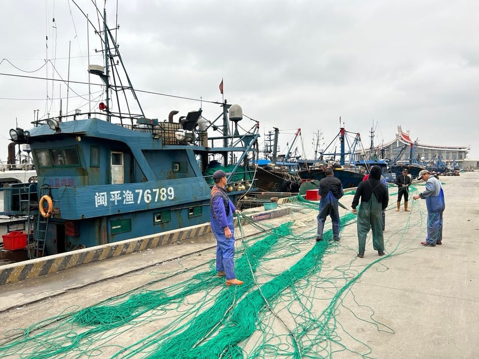 Fischer flicken ein Netz am Hafen. 