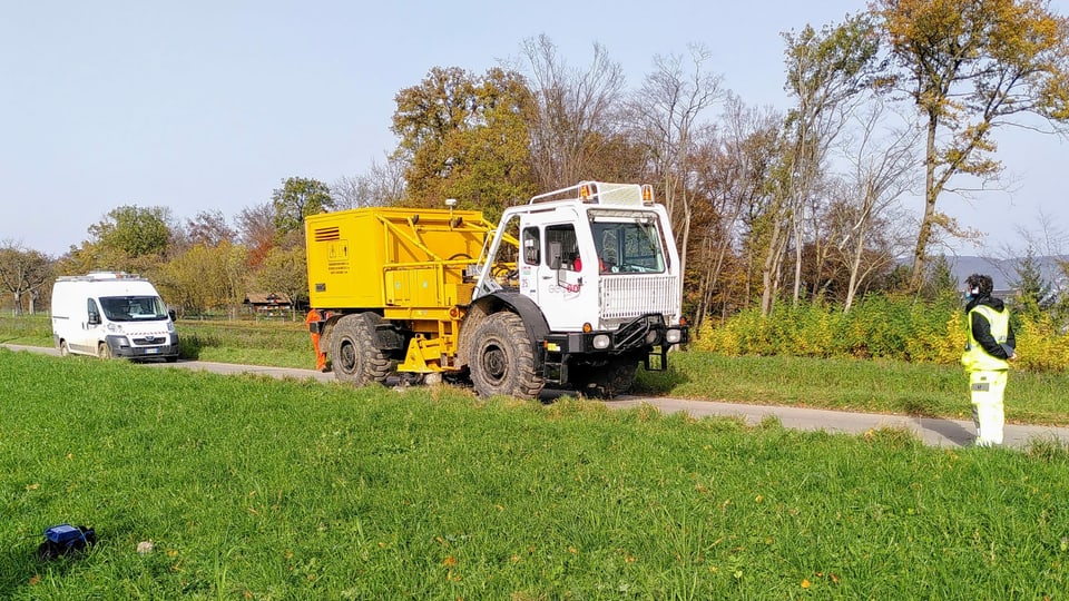 Weisses fahrzeug mit gelbem Aufbau auf schmalem Weg.