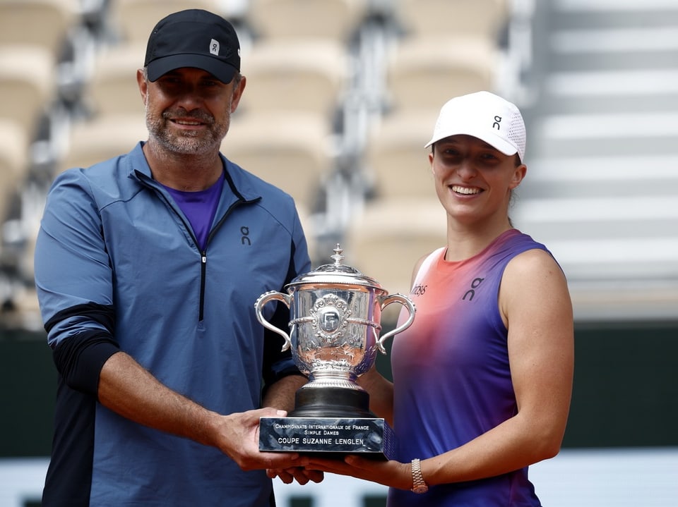 Zwei Personen halten gemeinsam einen Tennis-Pokal.