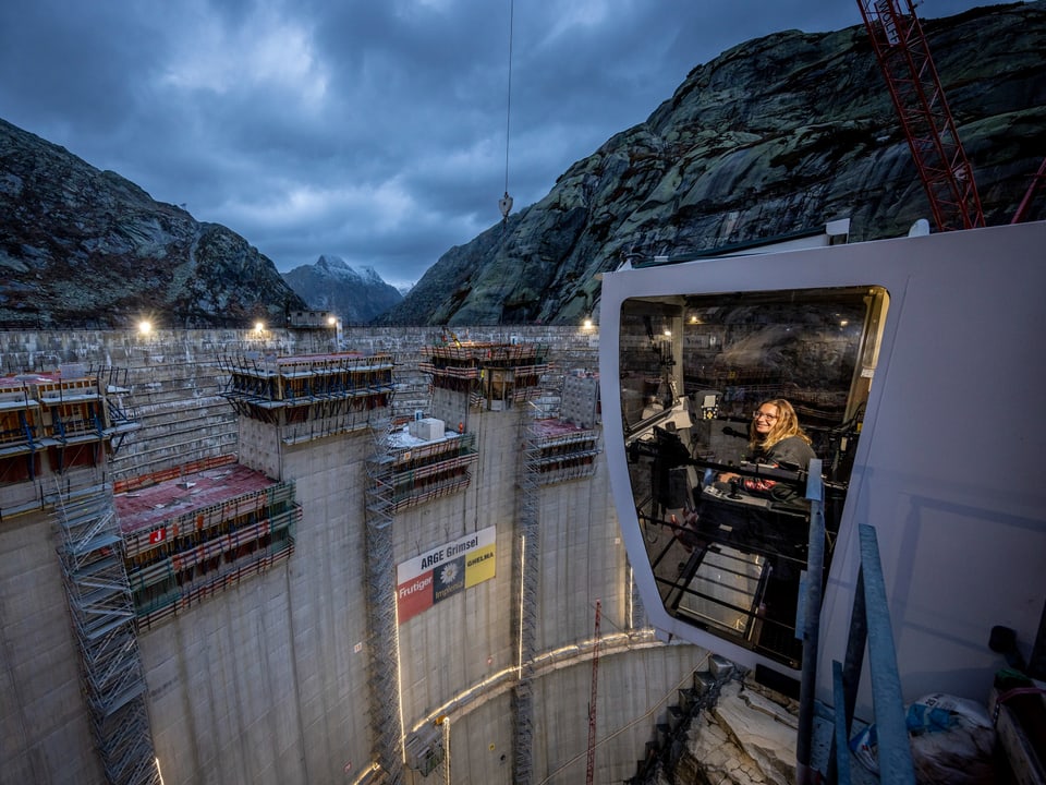 Baustelle zwischen Bergen mit Kranführer in Kabine.