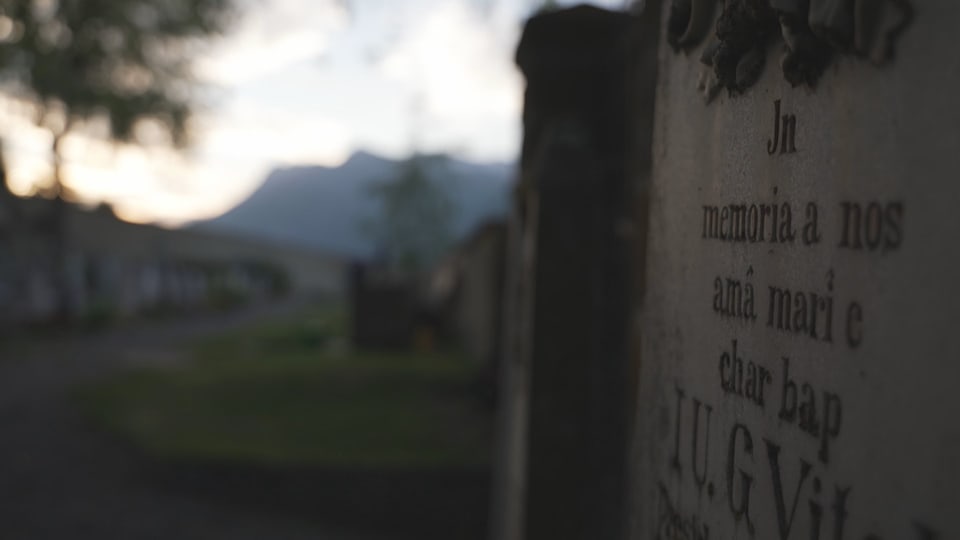 Nahaufnahme eines Grabsteins mit unscharfer Landschaft im Hintergrund.