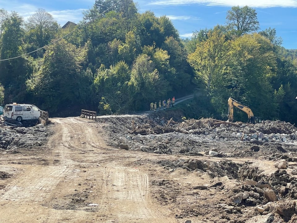 Baustelle im Wald mit Bagger und Lastwagen.