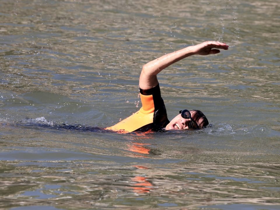 Person im Neoprenanzug schwimmt im Wasser.